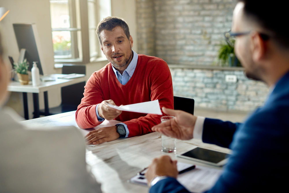 male candidate giving his cv member human resource team while having job interview office