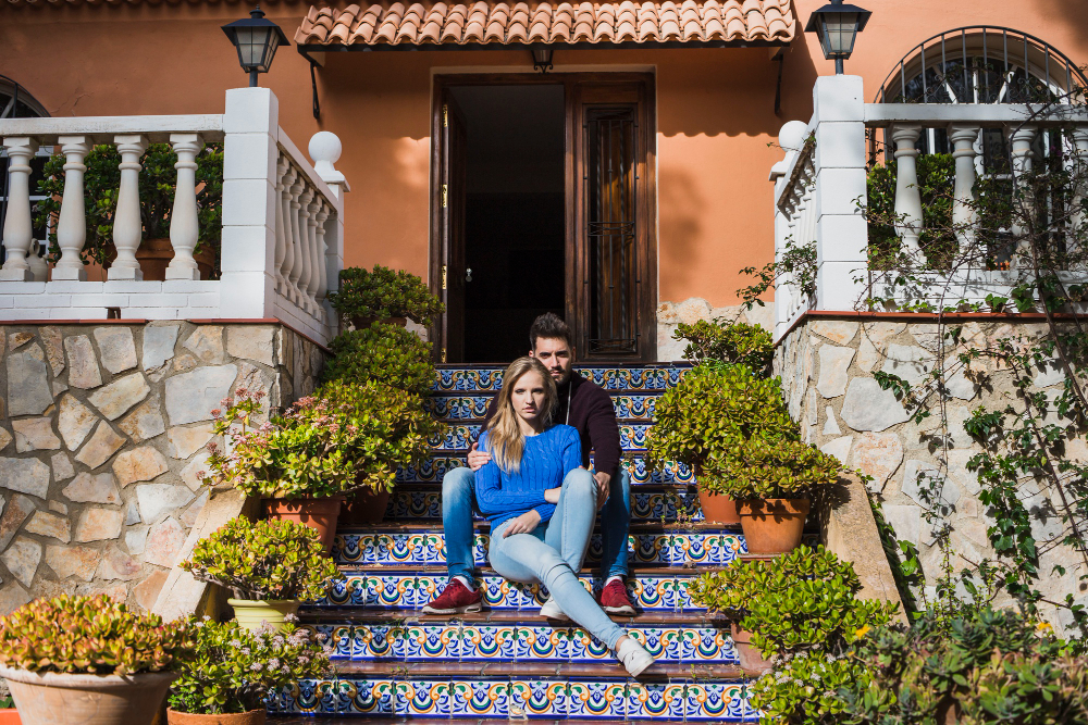 Couple sitting on the stairs outside a Spanish property