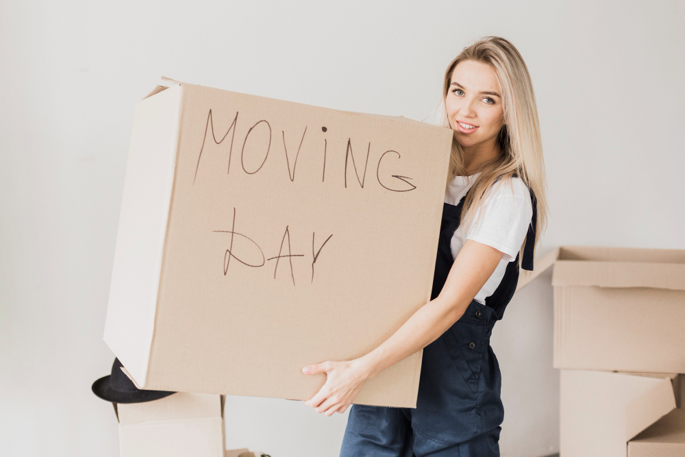 blonde woman carrying a box that says moving day