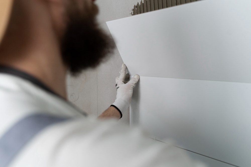 man putting on bathroom tiles in shower